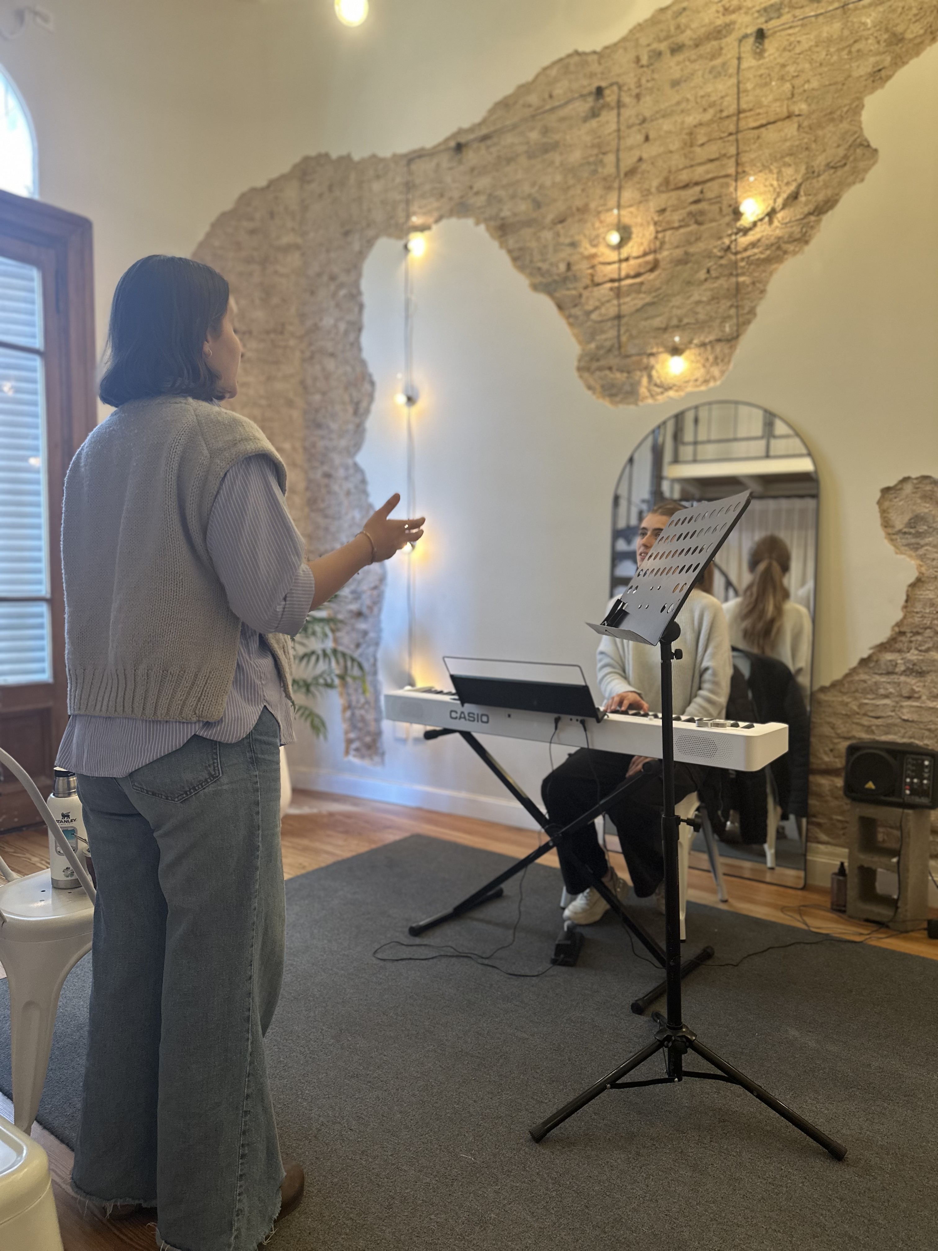 Alumna cantando mientras el profesor la acompaña en piano