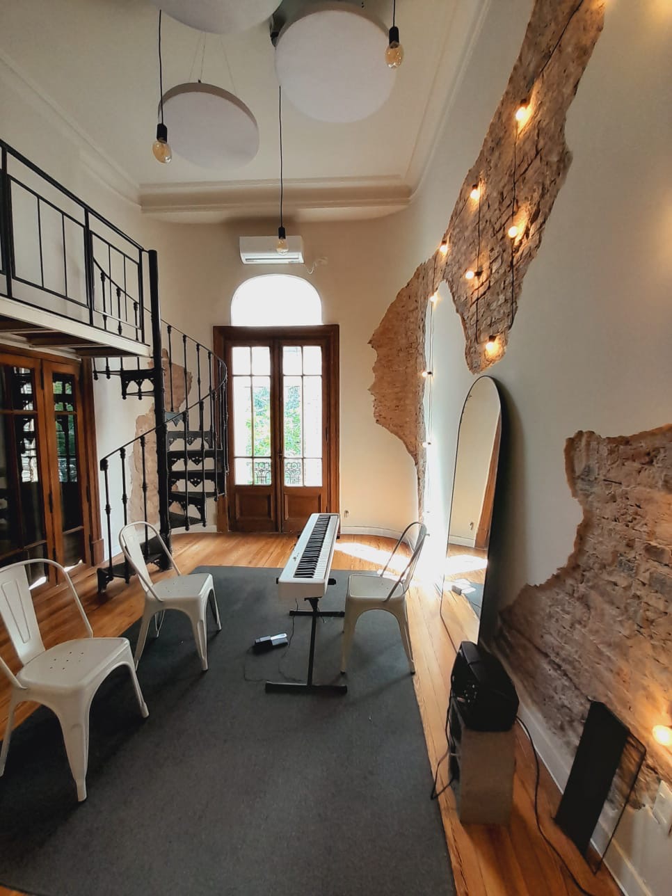 Sala principal con piano, muro de ladrillo y luces cálidas
