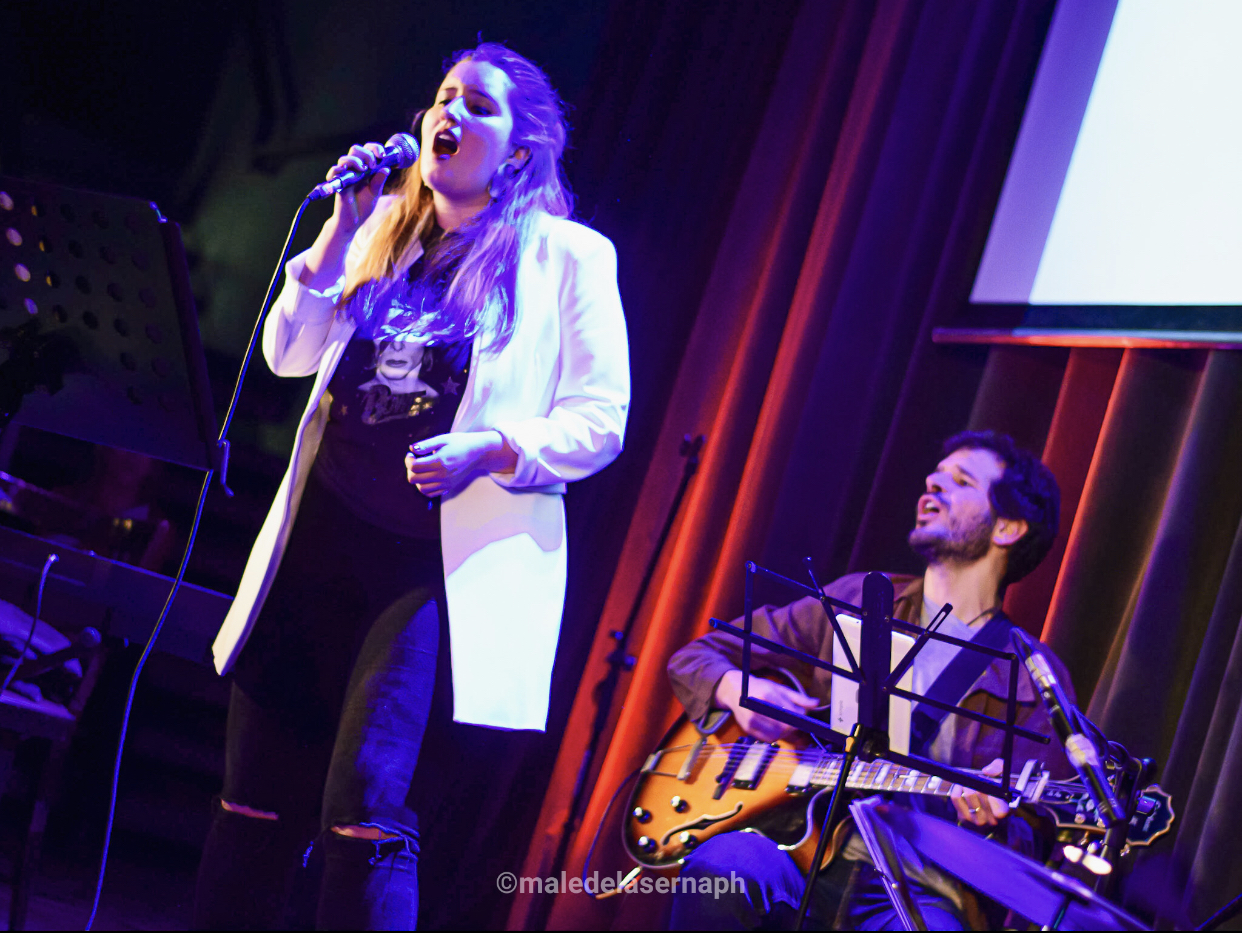 Cantante con banda en vivo, luces violetas